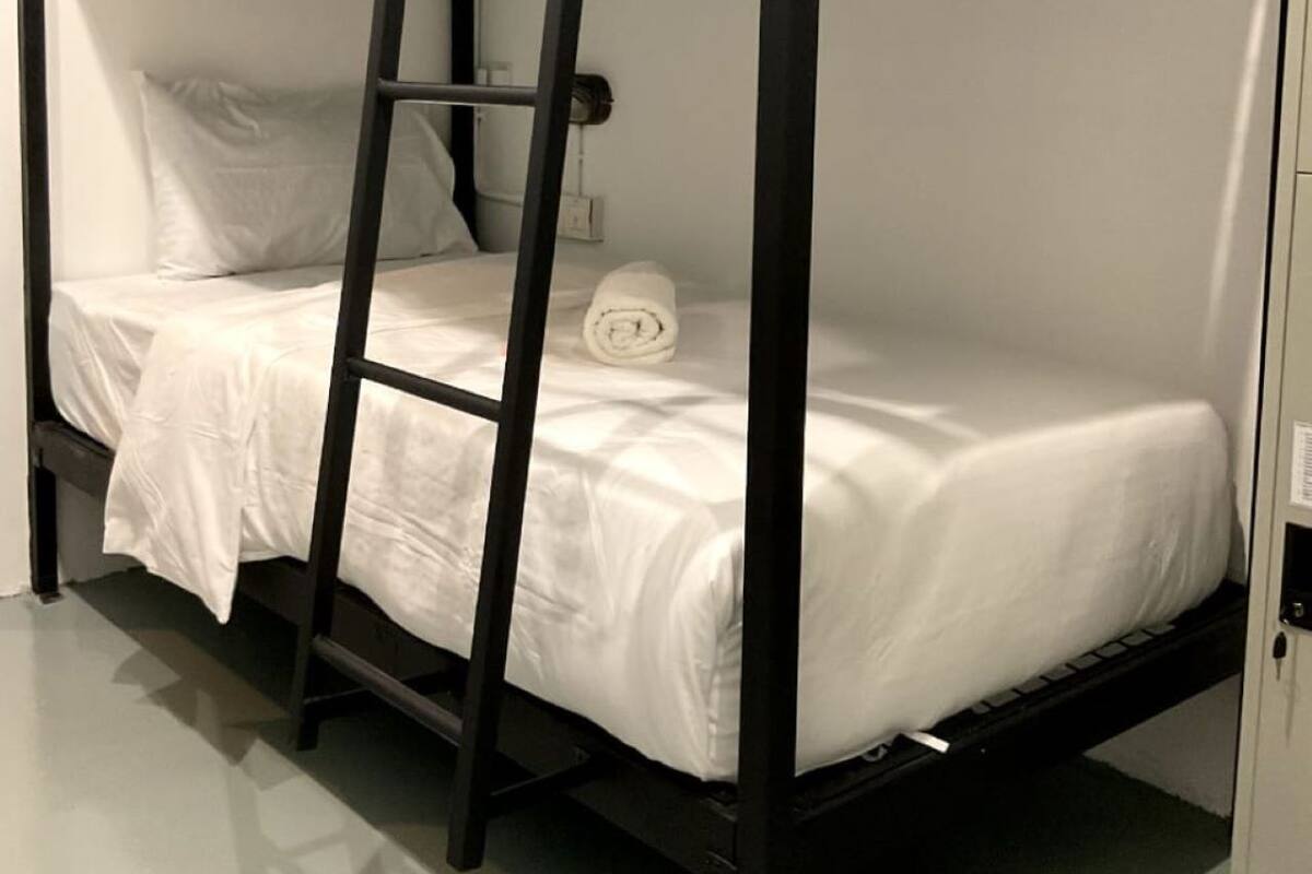 A bunk bed with a ladder, white bedding, and a rolled towel on the top bunk.