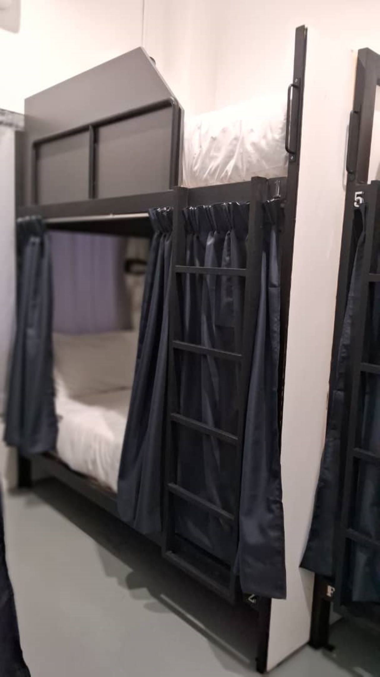 A bunk bed with black curtains and a white mattress.