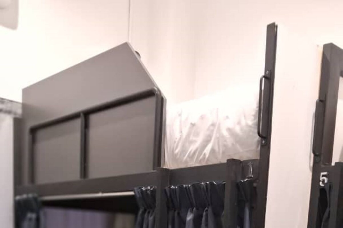 A bunk bed with black curtains and a white mattress.