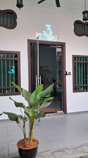 A hotel entrance with a neon sign, a potted plant, and a door with a number. - 39 Love Lane - Smart Intelligent Inn (George Town)