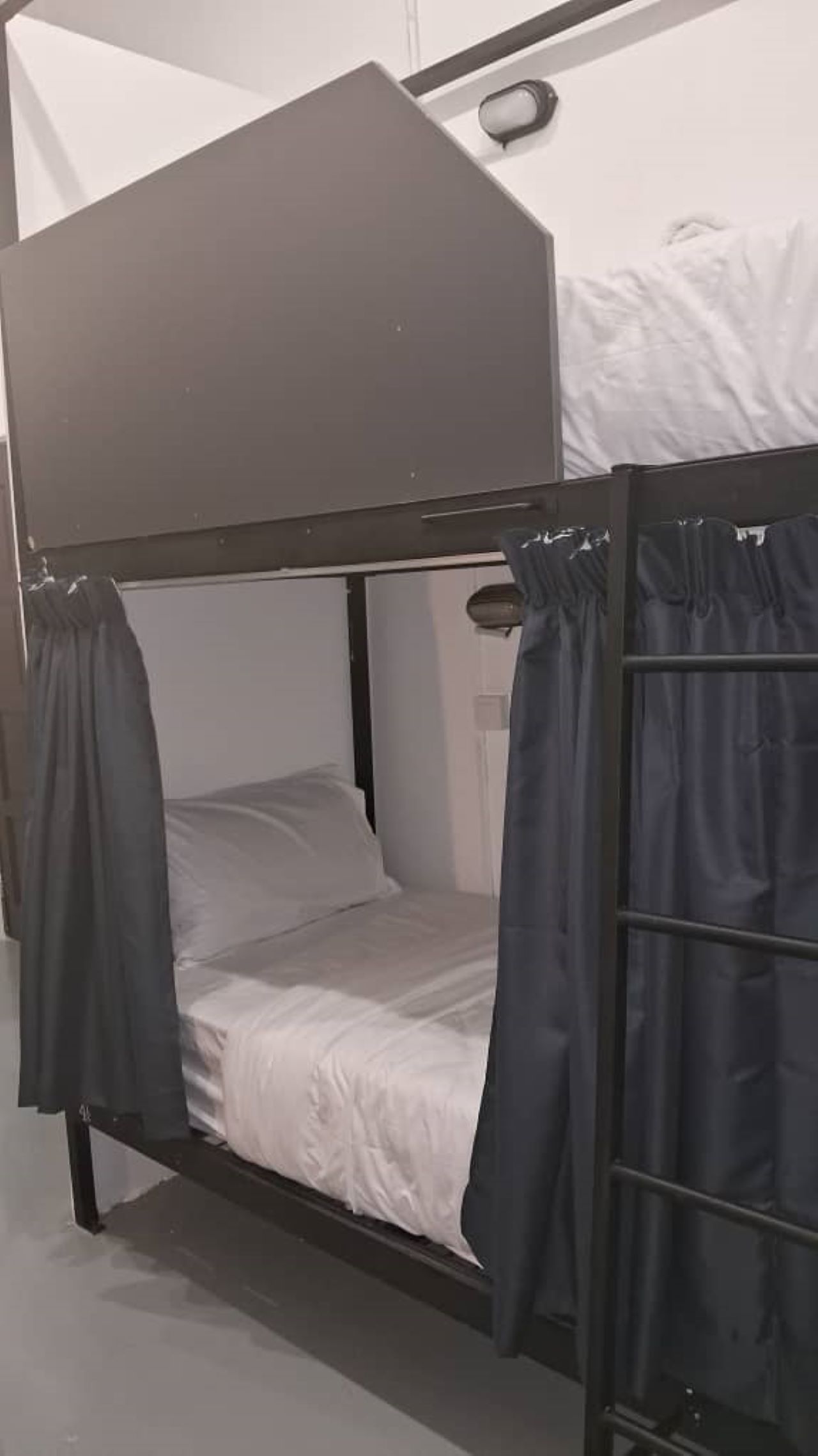 A bunk bed with a headboard, curtains, and a bedside table.