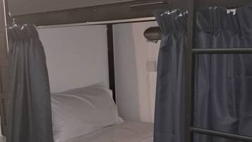 A bunk bed with a headboard, curtains, and a bedside table.