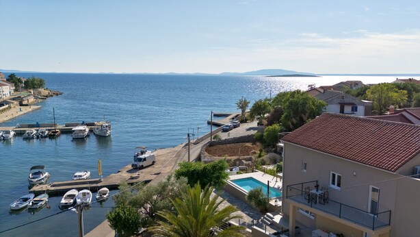 Zona residencial frente al mar, con un puerto deportivo, embarcaciones y una piscina.
