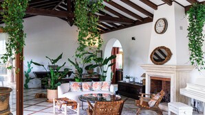 A spacious living area with a high ceiling, wooden beams, a fireplace, and a billiards table.