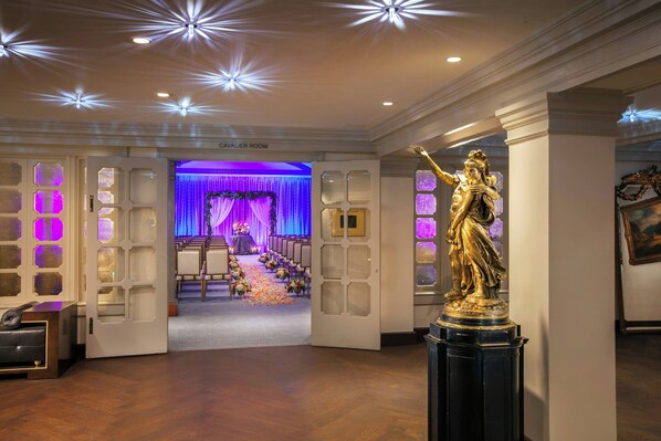 Een statig hotelterrein met een standbeeld, een receptiebalie en een zicht op de Cavalier Room.