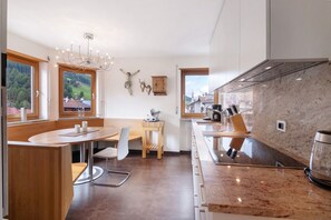 A modern kitchen with a marble countertop, wooden cabinets, and a view of the countryside. - Apartment 'Am Reschensee' with Mountain View, Balcony and Wi-Fi (San Valentino Alla Muta)