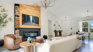 Una sala moderna con un sofá grande, un sillón de cuero, una chimenea y un televisor.