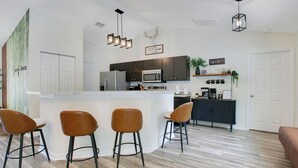 Una cocina moderna con una isla central, taburetes de bar e iluminación colgante.