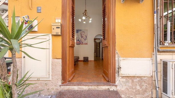 A doorway leading to a room with a tiled floor, a hanging light fixture, and a poster on the wall.
