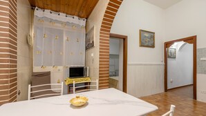 A dining area with a table, chairs, a microwave, and a kitchen visible through an archway.