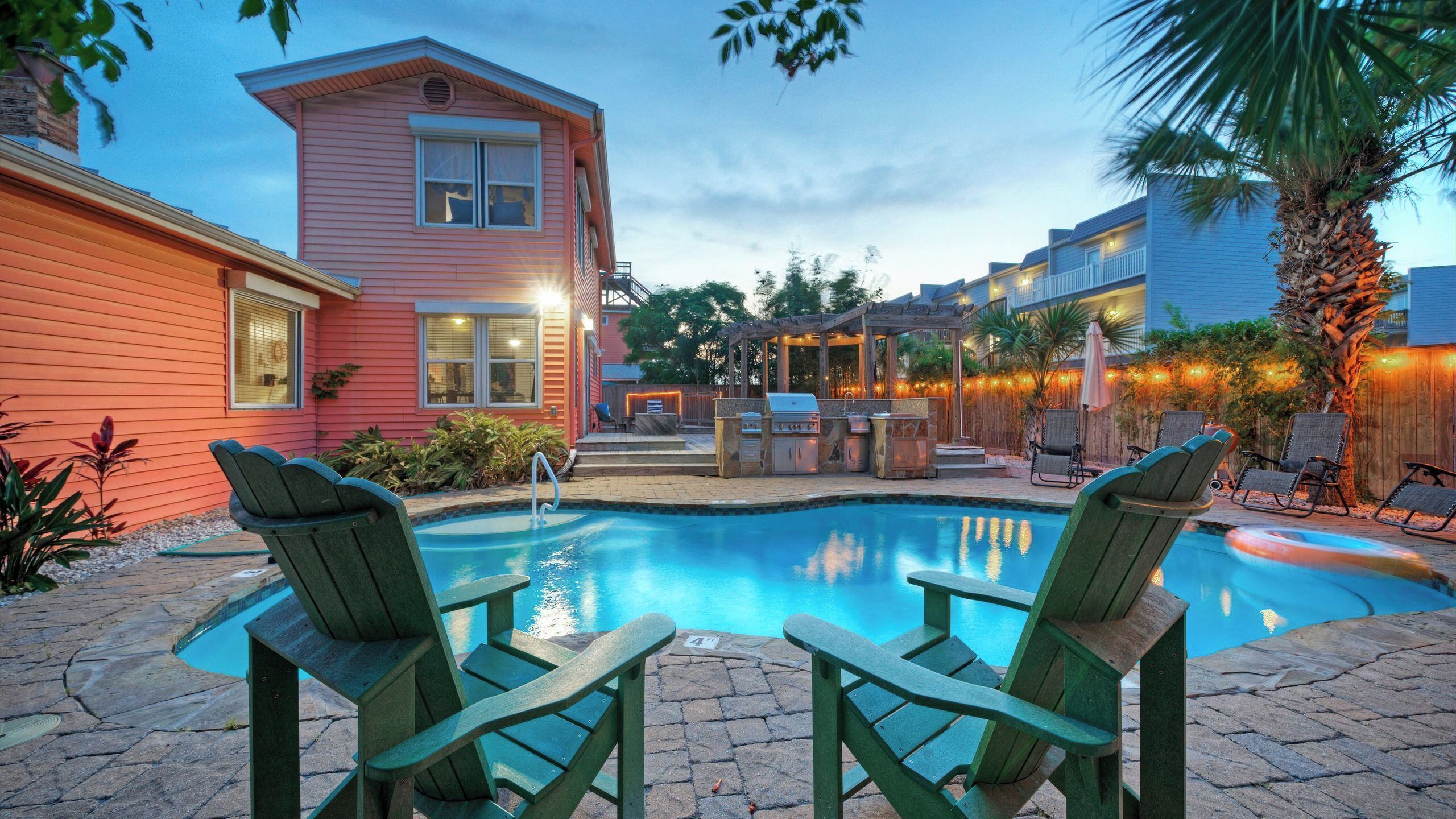 Ein Garten mit Pool, Sitzgelegenheiten im Freien und Grillplatz.