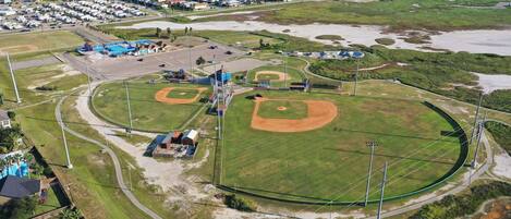 Vista aérea de um campo de beisebol com vários campos de defesa, um dugout e uma área de estacionamento.