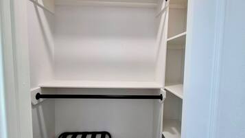 A walk-in closet with two black metal shelves and a black metal bench.
