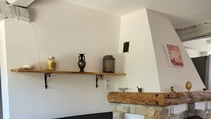 Ein Wohnzimmer mit Kamin aus Stein, einer schwarzen Couch und einem Holzregal mit Dekoration.