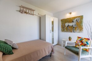 A bedroom with a bed, a chair, a desk, and a wardrobe.