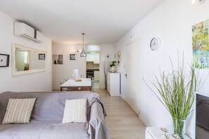 A modern living room with a grey sofa, a dining table, and a kitchen in the background.