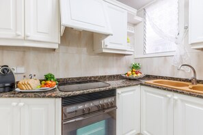 A modern kitchen with white cabinets, a Bosch oven, a granite countertop, and a sink.