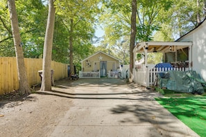 Un sentier en bois mène à un petit bâtiment surmonté d’une étoile, entouré d’arbres et d’une clôture blanche en piquets.