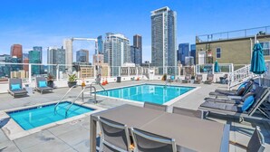 A rooftop pool area with lounge chairs and a view of the city skyline.
