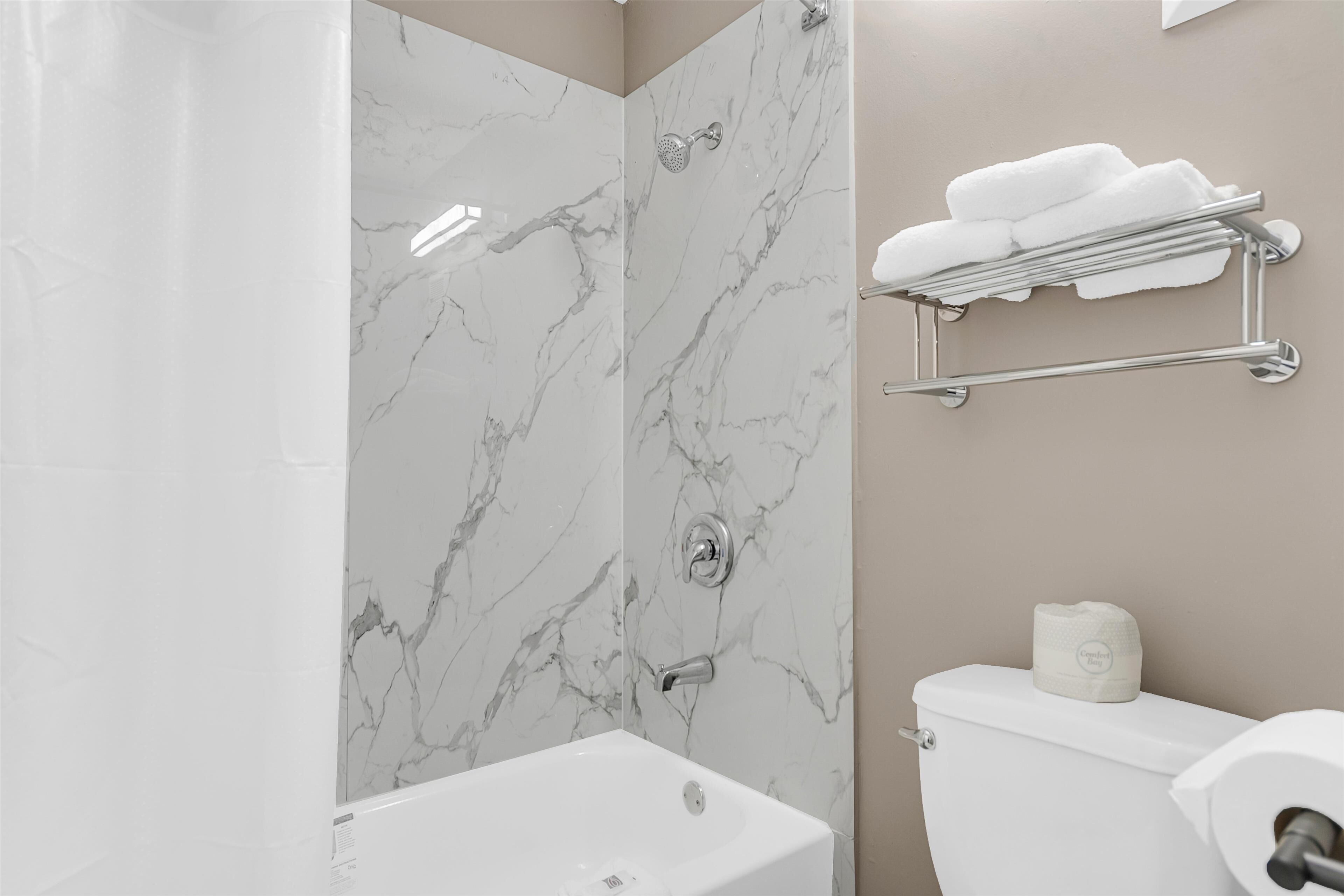 A bathroom with a shower, toilet, and a towel rack.