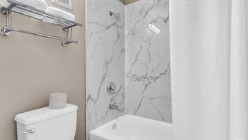 Un baño con inodoro, bañera y cortina de ducha.