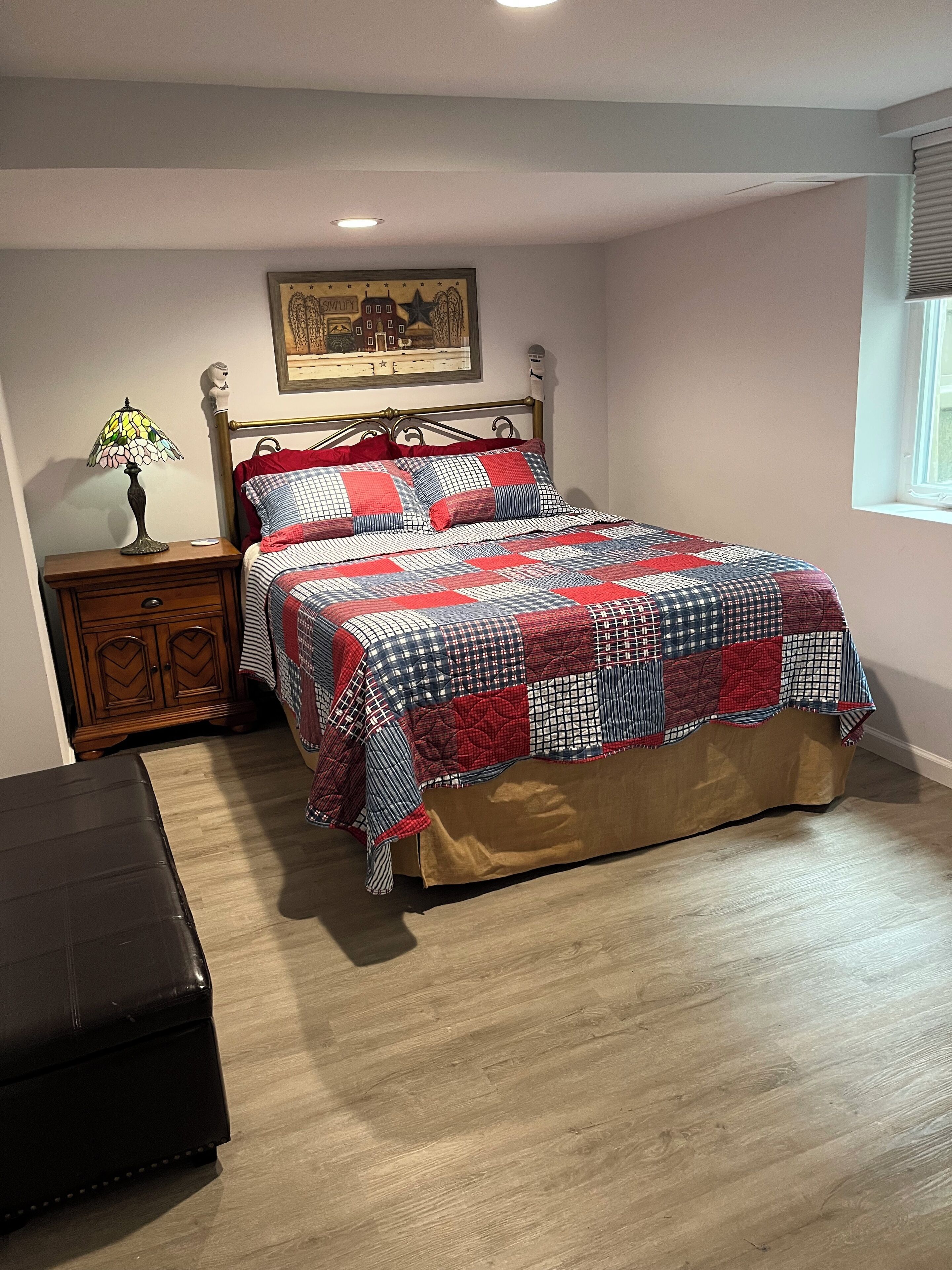 Un dormitorio con cama, mesita de noche, lámpara, cómoda y ventana.