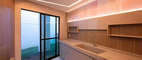 Una cocina moderna con un ventanal grande, un lavamanos empotrado y una pared decorativa de madera.