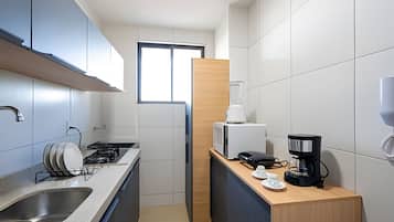 A compact kitchen with a sink, stove, microwave, and coffee maker.