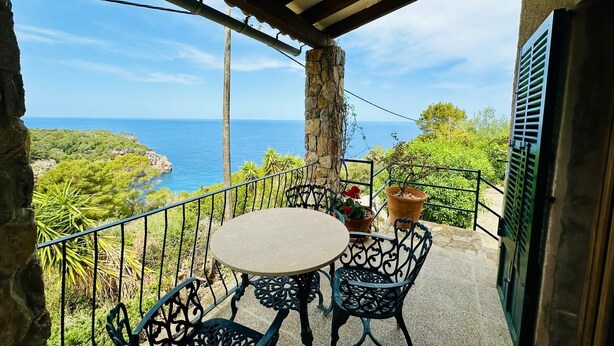 Varanda com mesa e cadeiras, com vista para a costa.