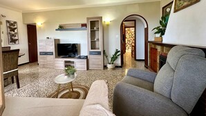 Sala de estar com televisão, sofá e uma mesinha com uma planta.