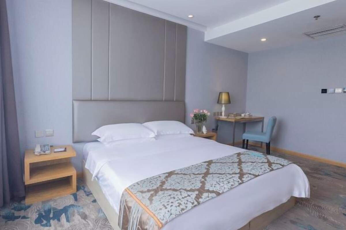 A hotel room with a bed, a desk, a chair, and a nightstand.