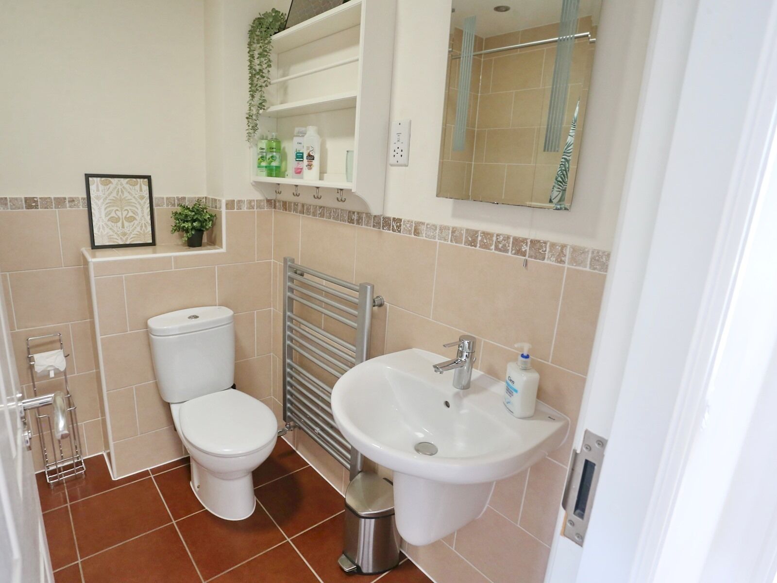 A bathroom with a toilet, sink, and a towel rack.