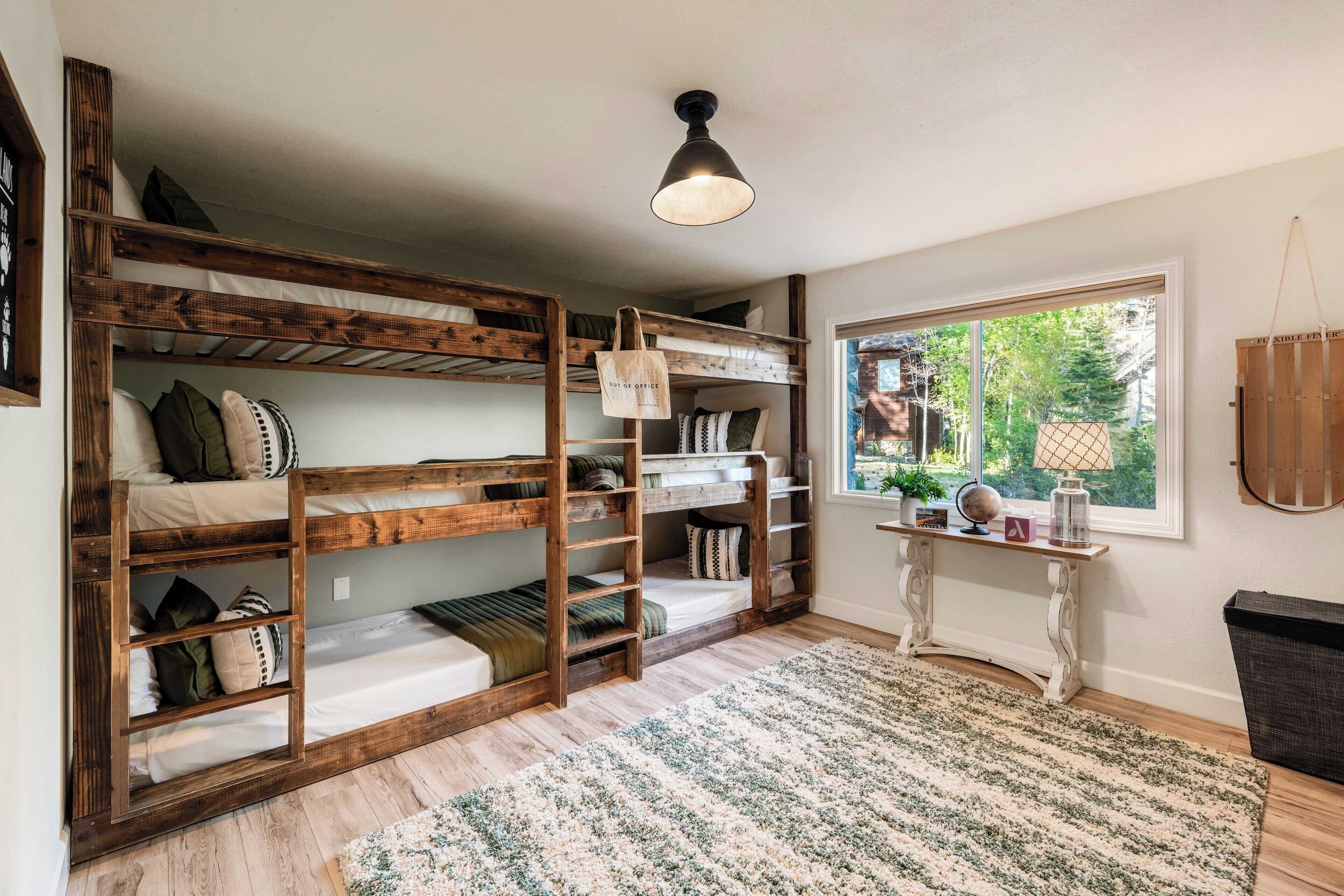 Een kamer met stapelbedden, een klein tafeltje met decoratieve objecten en uitzicht op groen buiten.