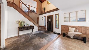 A spacious foyer with a stone floor, wooden staircase, and a bench with a cushion. - Geraldine Drive by Avantstay Hot Tub, Views, Walk to Trails + Game Room (Incline Village)
