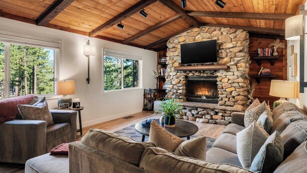 A cozy living room with a stone fireplace, a large flat-screen TV, and a comfortable seating area. - Geraldine Drive by Avantstay Hot Tub, Views, Walk to Trails + Game Room (Incline Village)