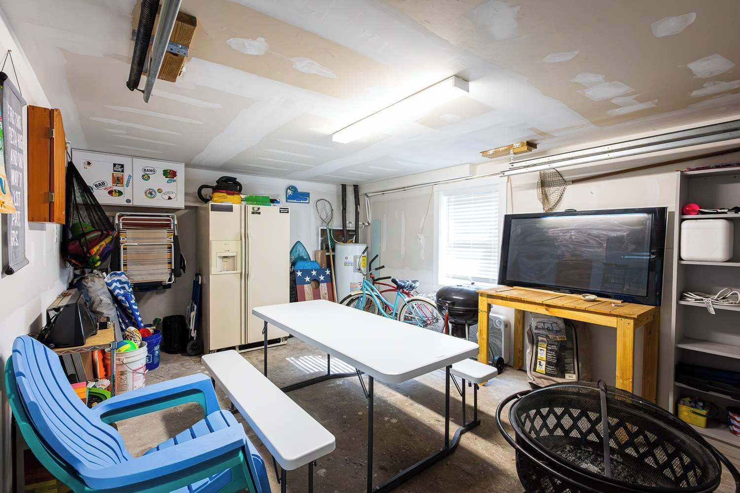 A compact, well-lit room with a white table, chairs, a TV, and a bicycle.