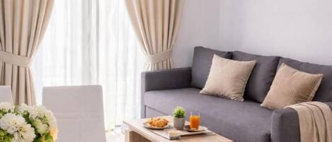 Una sala moderna con un sofá gris, una mesa de centro de madera y un jarrón con flores.