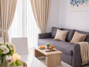 A modern living room with a grey sofa, a wooden coffee table, and a vase with flowers. -  All Inclusive Villa Four Pearls   (Seget Donji)