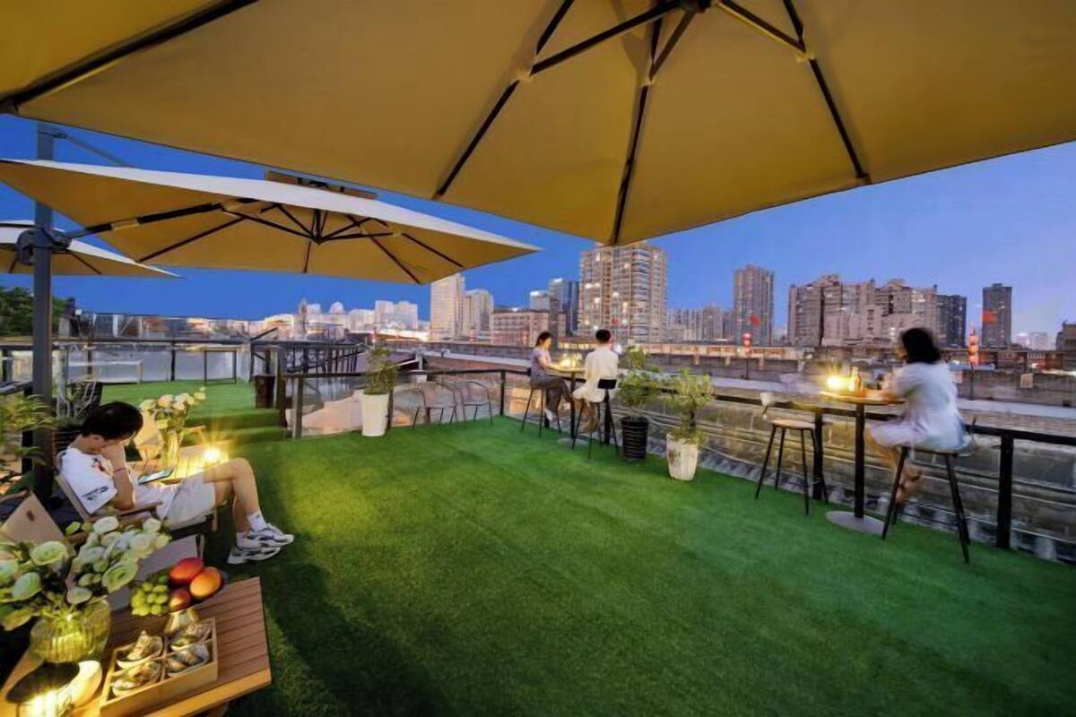 Una terraza en la azotea con césped artificial, mobiliario exterior y sombrillas.