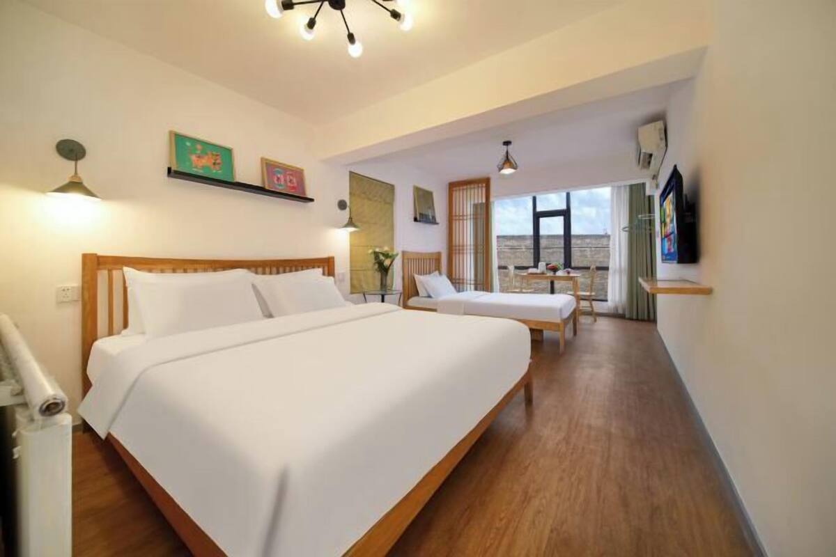 Habitación de hotel con una cama grande, una cama más pequeña, un escritorio y vistas al exterior.