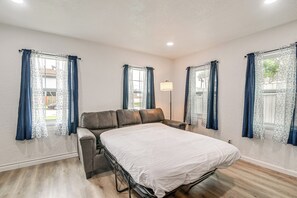 Ein Schlafzimmer mit einem Bett, einer Couch und Vorhängen.