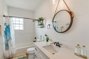 Ein modernes Badezimmer mit Badewanne, Toilette, Waschbecken und einem großen Spiegel.