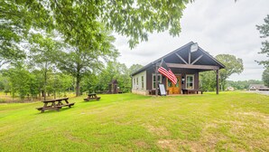 Ein rustikales Gebäude mit Veranda, einer amerikanischen Flagge und Picknicktischen auf einer grünen Wiese.