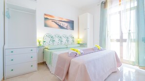 A bedroom with a bed, a nightstand, a dresser, a painting, and a window with curtains.