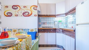 A kitchen with a tiled backsplash, wooden cabinets, and a dining area with a table set for two.