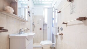 A modern bathroom with a shower, toilet, sink, and towel rack.