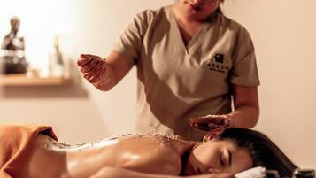 A person receiving a massage in a room with a statue and a shelf in the background.