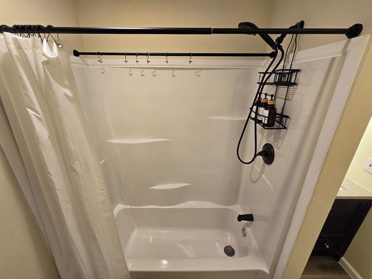 A shower with a black curtain rod, a showerhead, and a control panel.