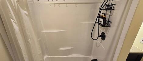 A shower with a black curtain rod, a showerhead, and a control panel.