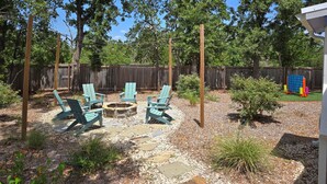 A backyard with a fire pit, outdoor seating, and a wooden fence.